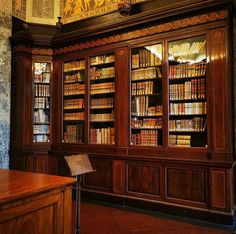 an old library with many books on it's shelves and paintings above the bookcases