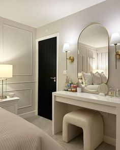 a bedroom with a bed, mirror and dressing table in front of the door that leads to another room