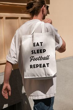 a man carrying a bag that says eat sleep football repeat