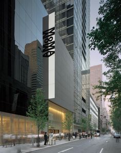 people are walking down the street in front of tall buildings and skyscrapers at dusk