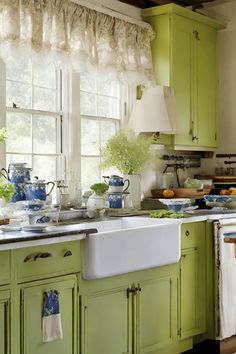 a kitchen filled with lots of green cabinets and white counter tops next to a window