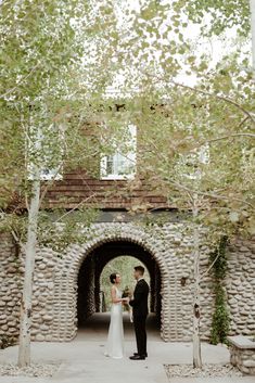 a bride and groom standing in front of an archway