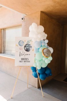 a sign with balloons attached to it in front of a building