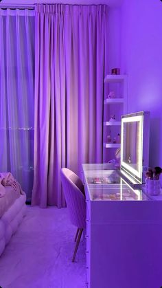 a bedroom with purple curtains and a desk in front of a window that has a mirror on it