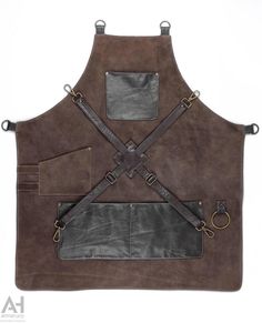 A brown suede cowhide leather apron with dark brown napalan leather pockets and leather crossed straps. The epitome of durability and sturdiness of an apron is presented to the leather-lovers. Simply add value to your profession by presenting yourselves with this leather apron. An apron that amazes by its simplicity and attracts all looks. A full length work apron is suitable for every professional who is really taking seriously his/her profession. Add class to your style and working appearance. Leather Aprons, Leather Aprons For Men, Brown Apron Cafe, Leather Shop Apron, Apron With Leather Straps, Work Aprons, Brown Cowhide, Leather Apron, Aprons For Men