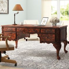 an antique desk with two chairs and a lamp