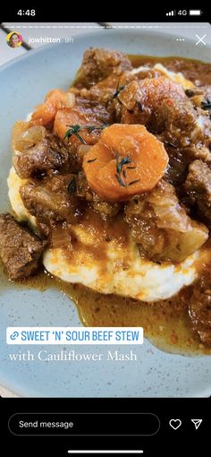 a blue plate topped with meat covered in gravy and carrots on top of mashed potatoes