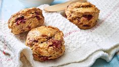 three muffins sitting on top of a white towel next to a bowl of yogurt