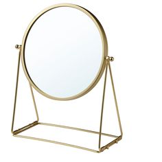 a gold metal stand with a round mirror on it's top and two legs