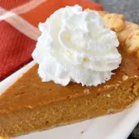 a slice of pumpkin pie with whipped cream on top