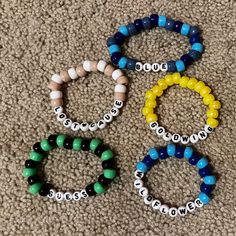 four bracelets with words on them sitting on the floor in front of a carpet