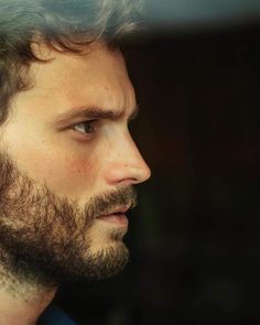 a close up of a man with a beard and blue shirt looking off into the distance