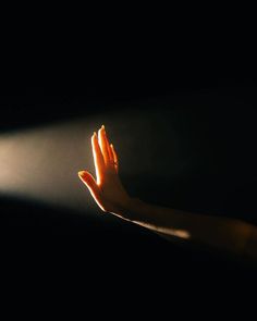 a woman's hand reaching up into the air with light coming from behind her