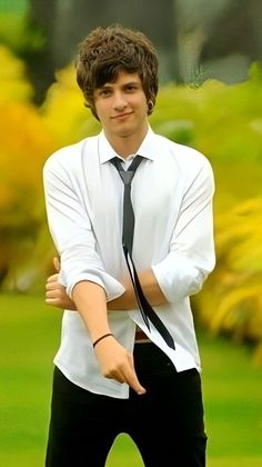 a young man wearing a white shirt and black tie posing for the camera with his arms crossed