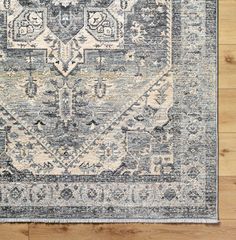 a blue and beige area rug with an ornate design on the center, surrounded by wood flooring