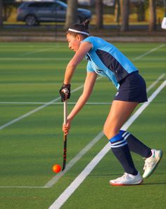 a woman playing field hockey with an orange ball