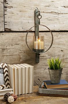 a table topped with books and candles next to a potted plant on top of a wooden