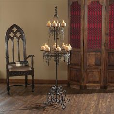 a candle holder with candles on it in front of a chair and wooden flooring