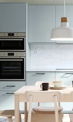 a white kitchen with an oven, table and chairs in front of the stoves