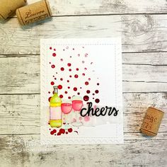 some wine corks are next to a card with cheers written on it and two glasses of wine