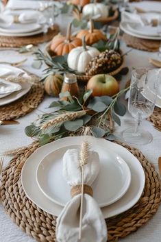 Thanksgiving table setting perfect for small spaces: a close up of a nordic themed table decor for thanksgiving, with woven chargers, white ceramic plates, white linen napkin elegantly folded and a woven napkin ring with one wheat stalk . The centrepiece is: pumpkins and fruits in an charming woven basket, seasonal foliage. Modern Thanksgiving Table Settings, Thanksgiving Table Setting Ideas, Thanksgiving Dinner Plates, Fall Dining Table Decor, Thanksgiving Dinner Table Decorations, Simple Thanksgiving Table, Food Display Table