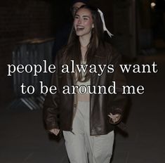 a woman walking down the street wearing a brown leather jacket and white pants with text that reads people always want to be around me