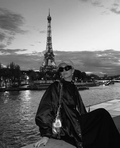 a woman sitting next to the eiffel tower