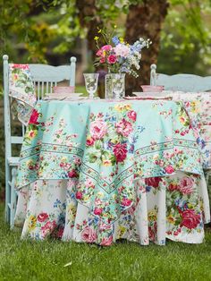 a table with flowers on it and two chairs in the grass next to each other