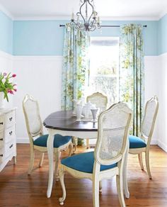 a dinning room table with blue chairs and white furniture in front of a window