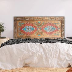 the bed is made up with white linens and an intricate wooden headboard above it