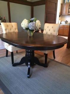 a dining room table with two chairs and flowers on the centerpiece in front of it