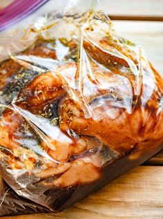 a loaf of bread wrapped in plastic sitting on top of a wooden table