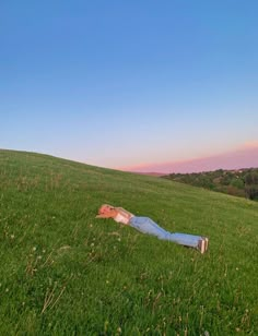 a person laying in the grass on top of a hill