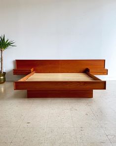 a bed sitting on top of a white floor next to a potted plant