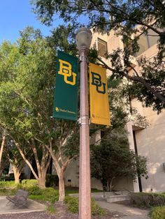 a pole with two signs on it in front of a building and trees near by