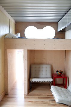 the interior of a tiny house with wood flooring and white furniture, including a couch