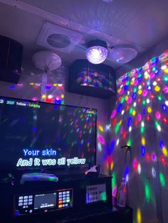 a room with colorful lights on the ceiling and a large television screen in front of it