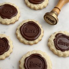 cookies with chocolate stamp on them sitting next to a rolling pin and cookie cutters