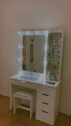 a white vanity with lighted mirror and stool