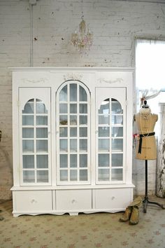 an old white china cabinet with glass doors