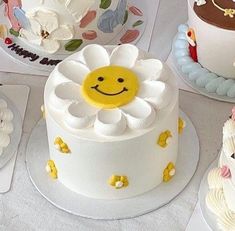 a table topped with lots of cakes covered in frosting and decorated like smiley faces