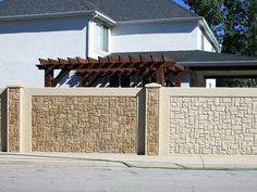 a tan brick fence with an attached pergolan