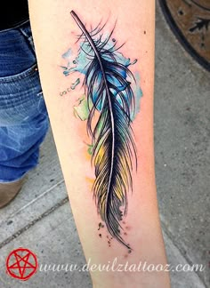 a watercolor style feather tattoo on the leg