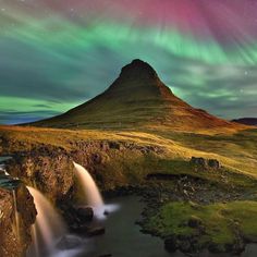 the aurora lights over a waterfall in iceland