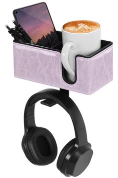 a cup of coffee and headphones in a holder with a cell phone on it