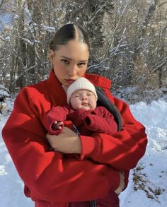 a woman holding a baby in the snow