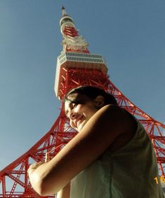 a woman standing in front of a tall red tower