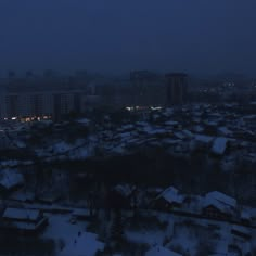 the city is covered in snow at night, with buildings lit up on either side