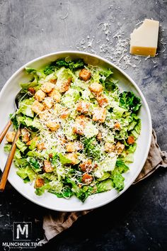 a salad with cheese and lettuce in a white bowl on a gray table