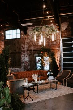 a room filled with lots of furniture and lights hanging from the ceiling next to plants